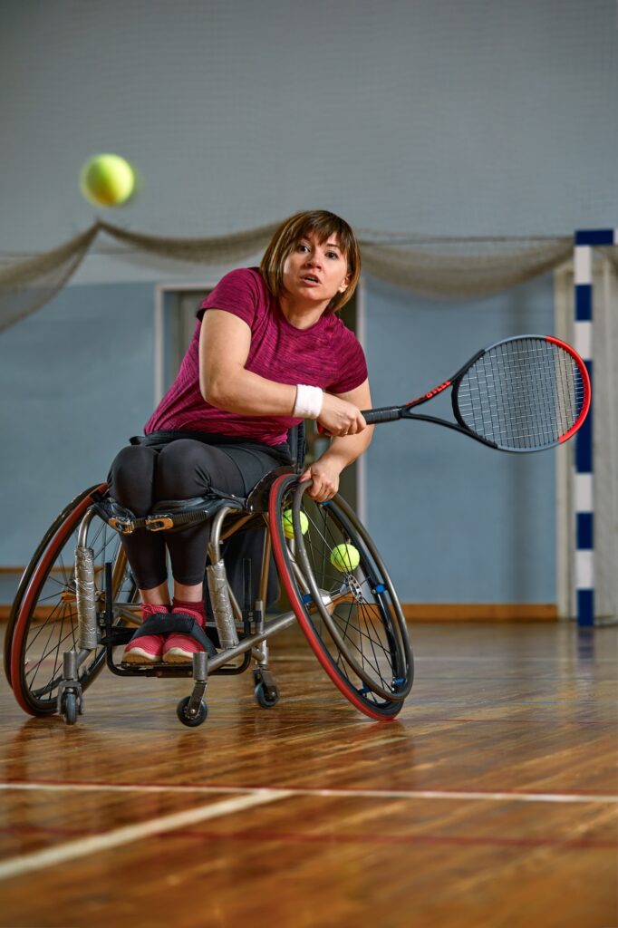 young woman with a physical disability playing tennis on wheelchair on tennis court